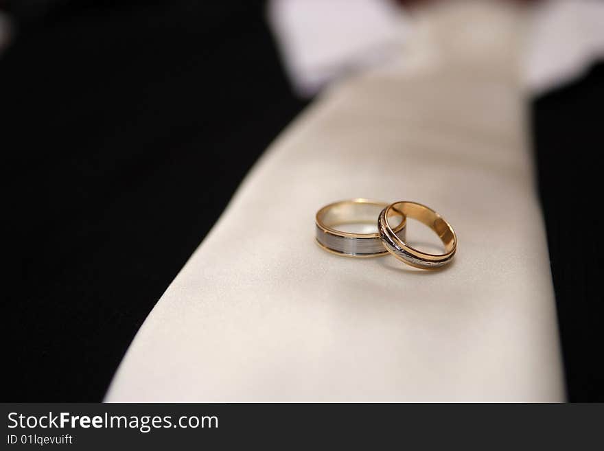 Wedding rings resting on  grooms tie