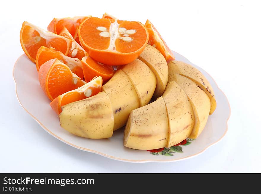 Cut bananas and mandarines on a white dish