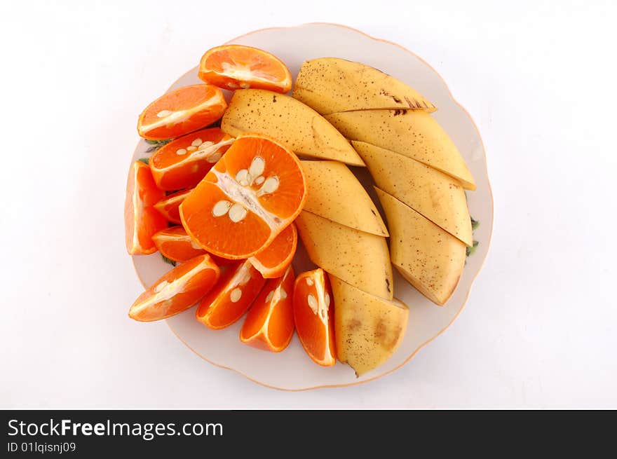 Cut bananas and mandarines on a white dish