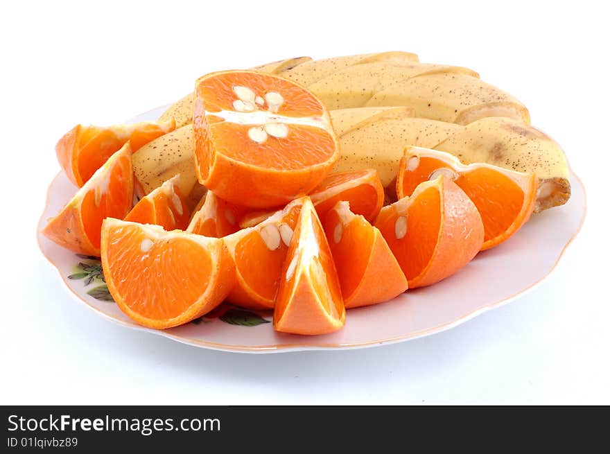 Cut bananas and mandarines on a white dish