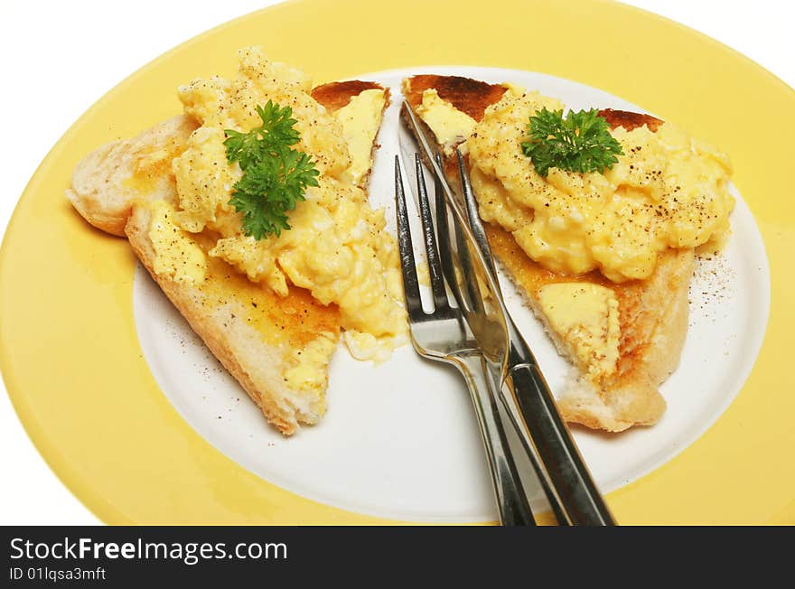 Scrambled eggs on toast with knife and fork on a plate