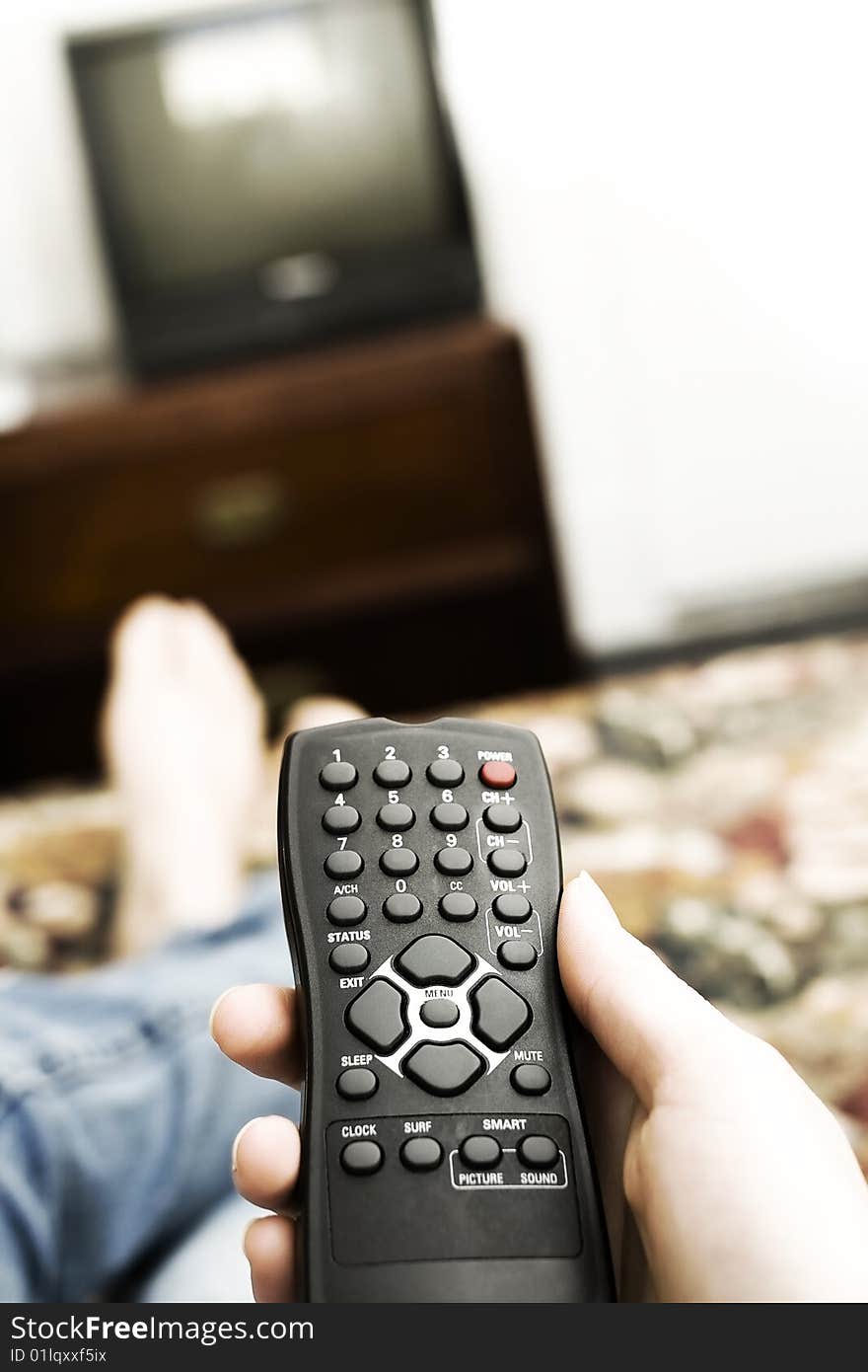 A hand holding a controller raised to change the station or turn the television on. A hand holding a controller raised to change the station or turn the television on.