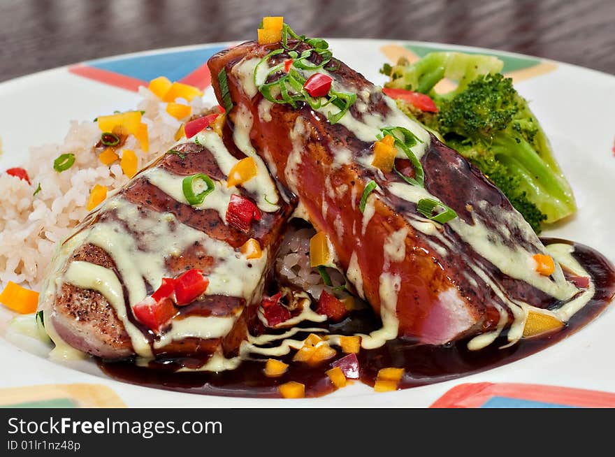 Dish with grilled tuna fillets over rice with vegetables and red wine reduction and Hollandaise sauce. Dish with grilled tuna fillets over rice with vegetables and red wine reduction and Hollandaise sauce