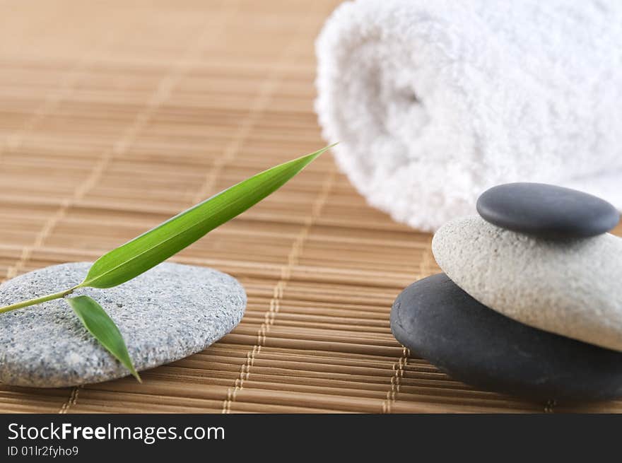 Bamboo leaf and stones on a bamboo mat with towel in the background. Bamboo leaf and stones on a bamboo mat with towel in the background