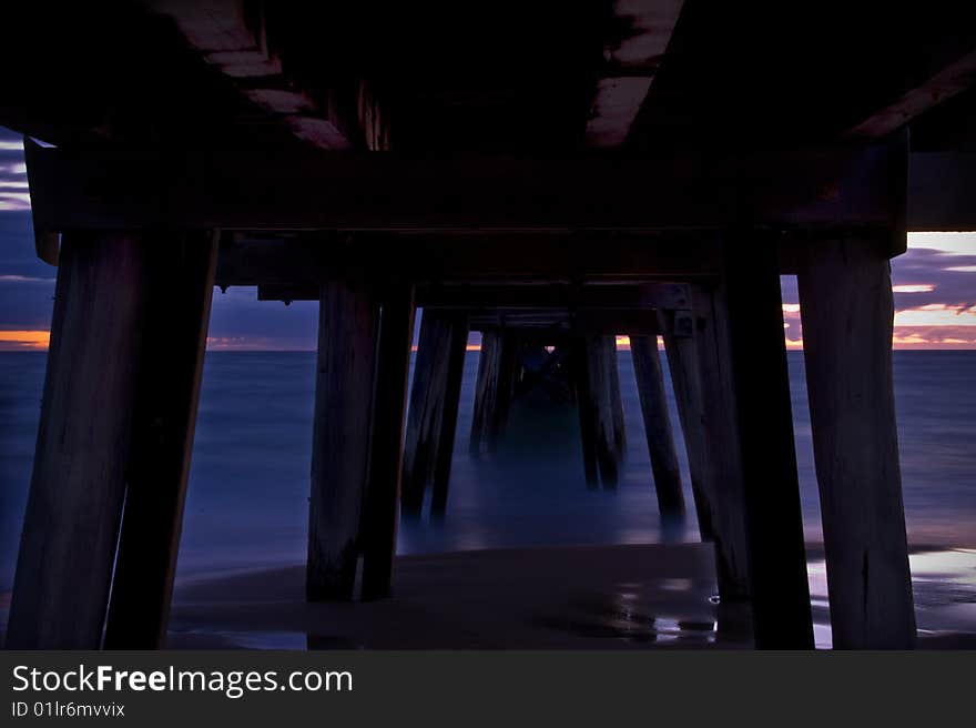 A jetty at sunset with beach, ocean and sky. Men fishing from jetty also. A jetty at sunset with beach, ocean and sky. Men fishing from jetty also.