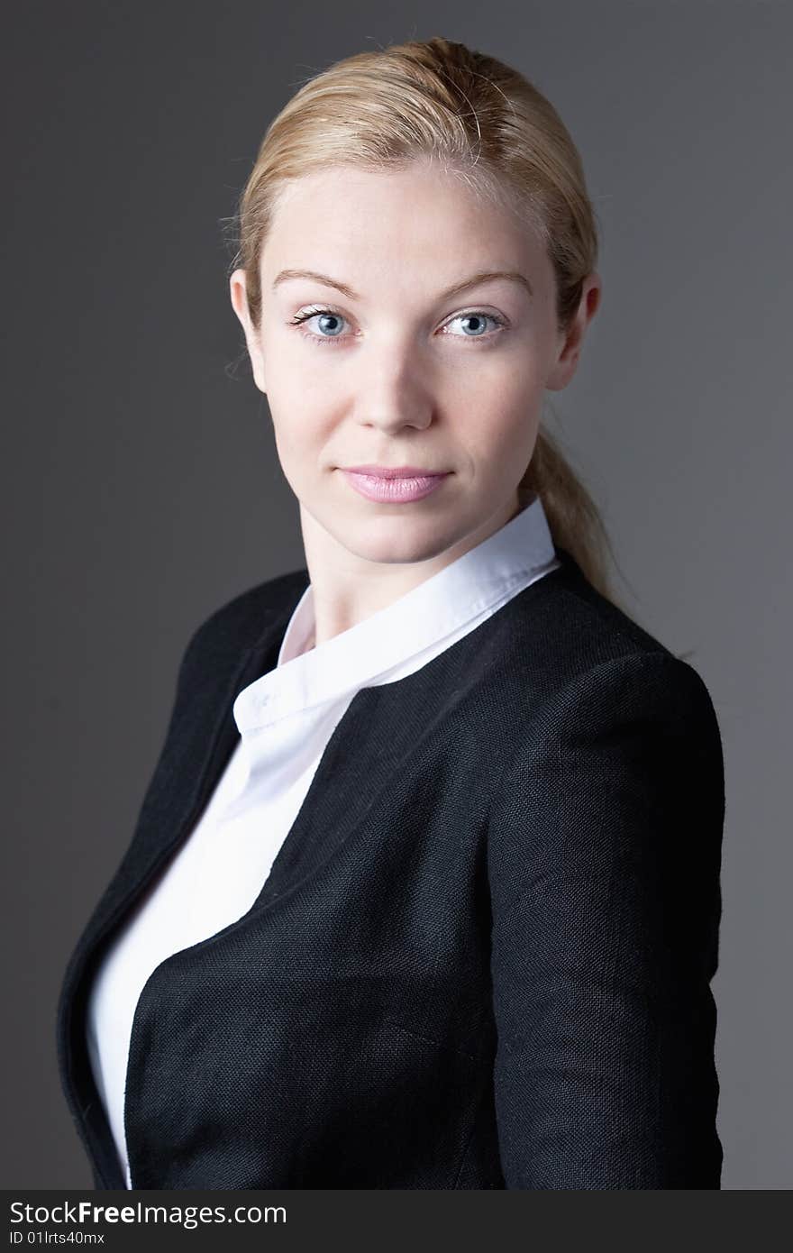 A portrait of a blue eyed blonde haired businesswoman on a gray background