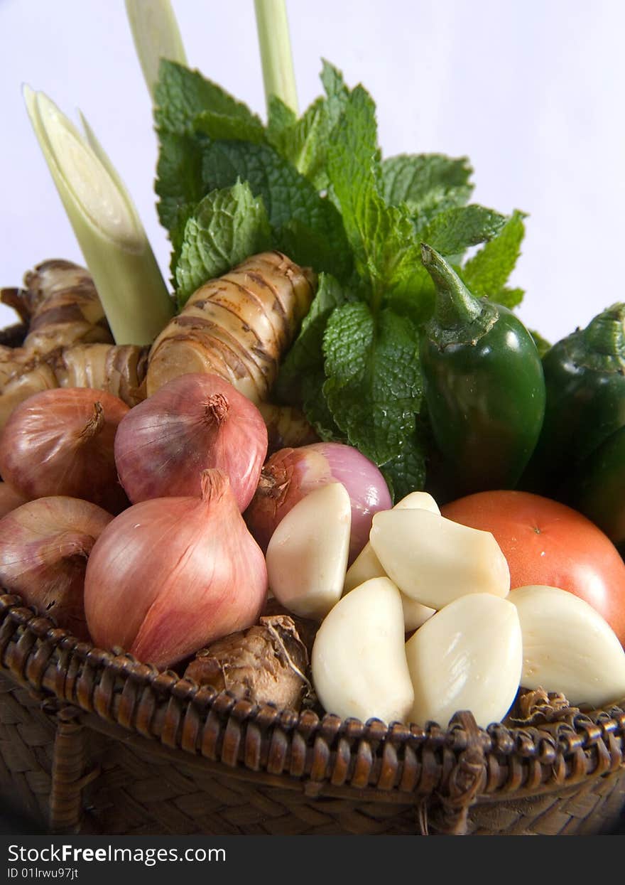 Fresh basket of herbs and vegetables with a white background