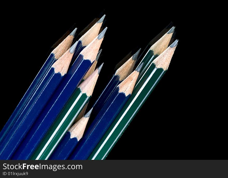 Kit of green and blue pencils on black background