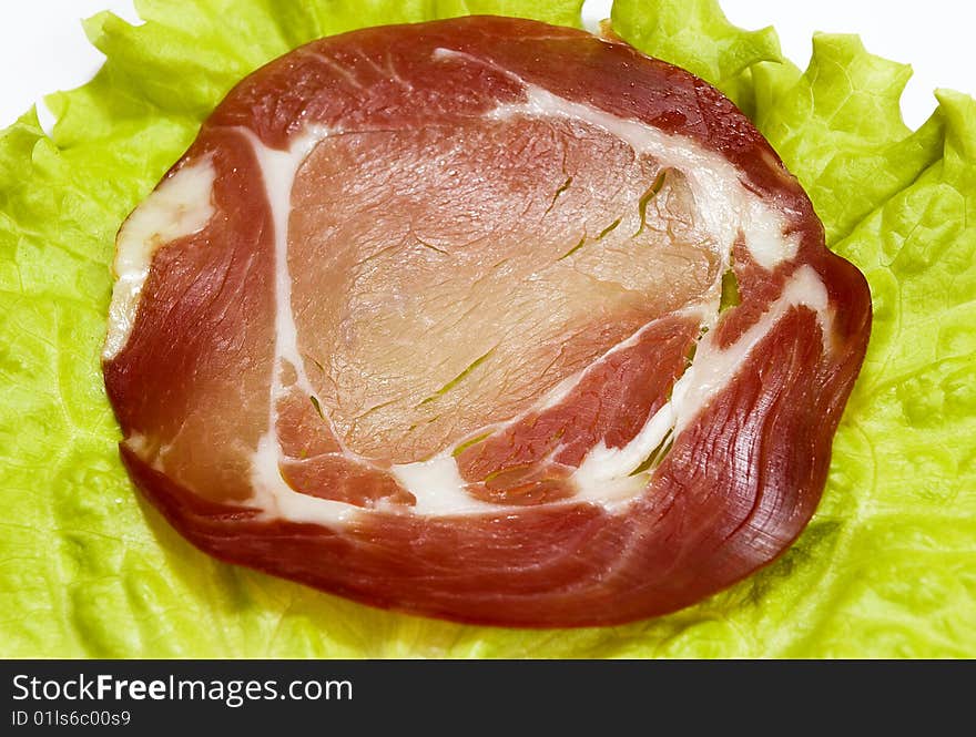 Slice of the smoked meat on the green sheet of lettuce