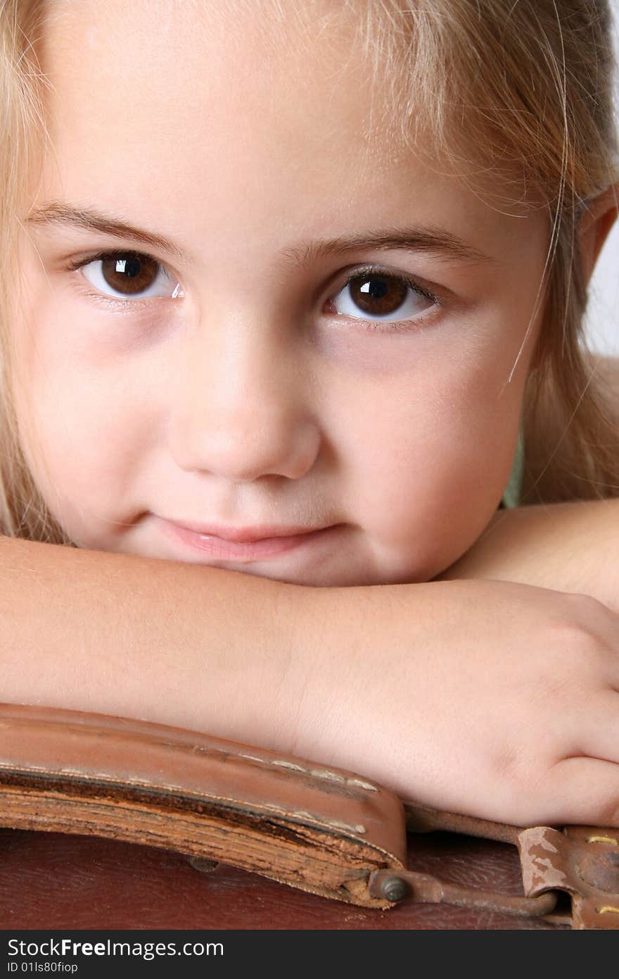 Beautiful young girl resting on an antique suitcase. Beautiful young girl resting on an antique suitcase