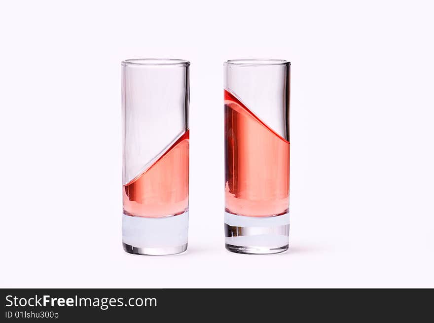 Thin glasses with pink liquid on white background