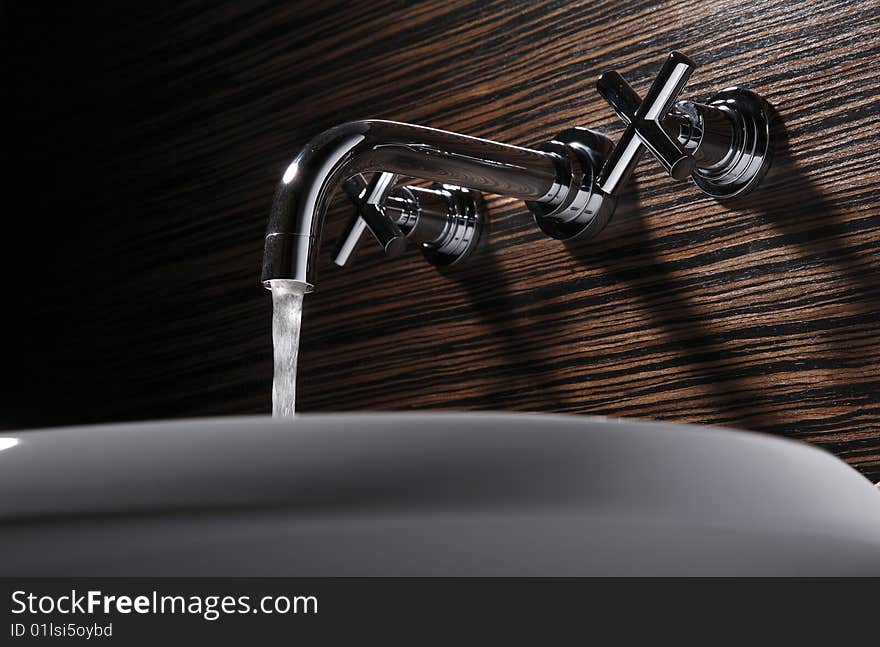 The faucet is watering,wood background.