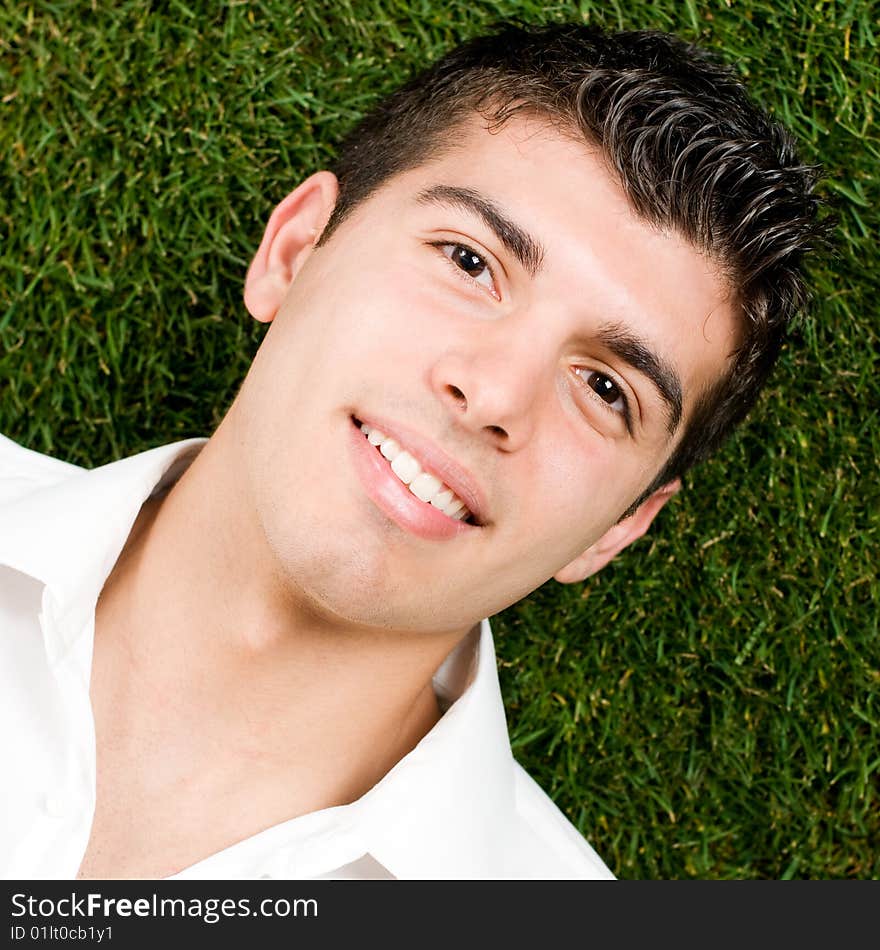 Close up of young handsome man relaxing outdoor lying on back on green grass. Close up of young handsome man relaxing outdoor lying on back on green grass