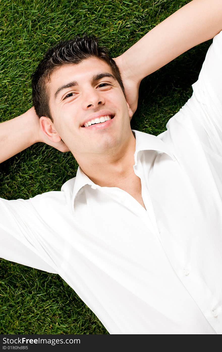 Young handsome man relaxing outdoor lying on back on green grass. Young handsome man relaxing outdoor lying on back on green grass