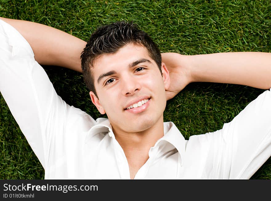 Young handsome man relaxing outdoor lying on back on green grass. Young handsome man relaxing outdoor lying on back on green grass