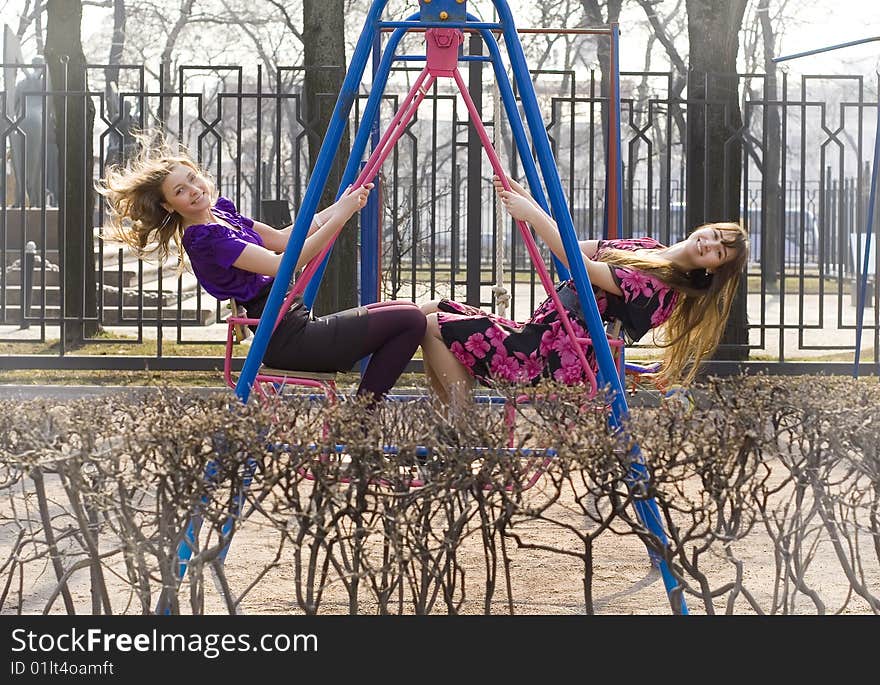 Blonde and brunette on swings