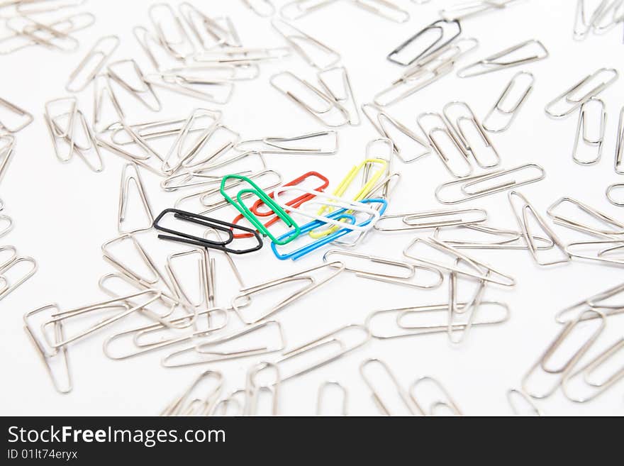 Five colourful paperclips among many steel grey paperclips on white background. Five colourful paperclips among many steel grey paperclips on white background