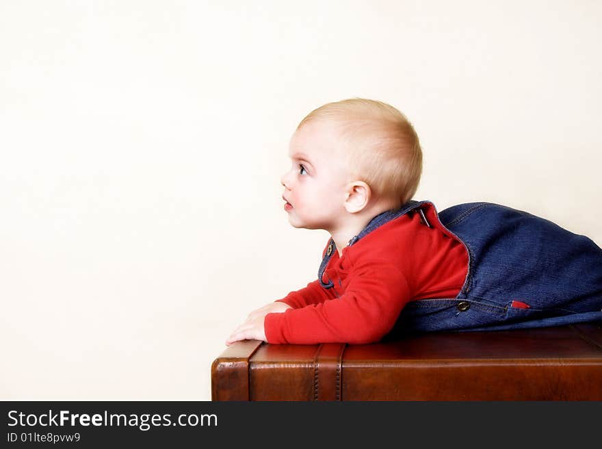 Baby boy lying on an old style trunk