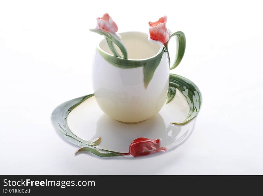 Saucer, cup and spoon decorated with red flower and green color. Saucer, cup and spoon decorated with red flower and green color