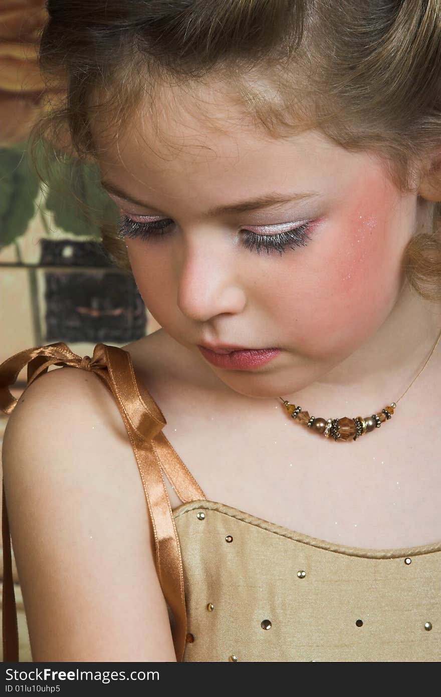 Blond Flower girl wearing a golden dress with beadwork