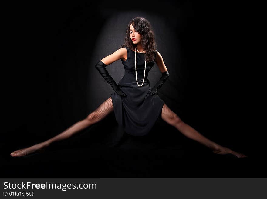 Fine art portrait of girl with long legs with perl against black background