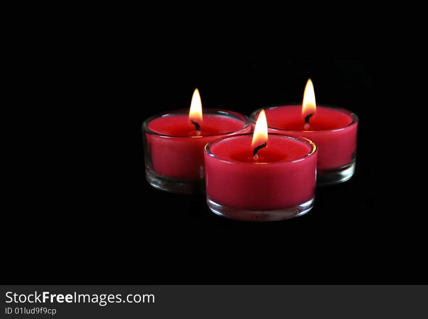 Three lit candles on a black background