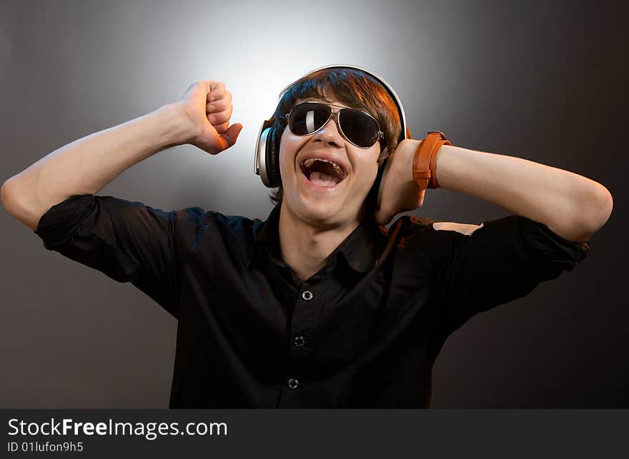 Young screaming caucasian dj with headphones over grey background. Young screaming caucasian dj with headphones over grey background