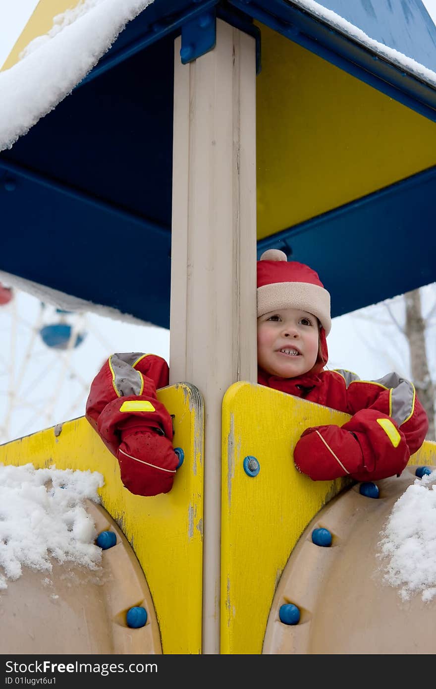 Little girl looks forward in multicolored construction at the playground. Little girl looks forward in multicolored construction at the playground