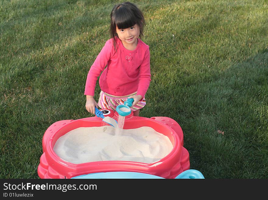 Asian Girl playing in a sand table