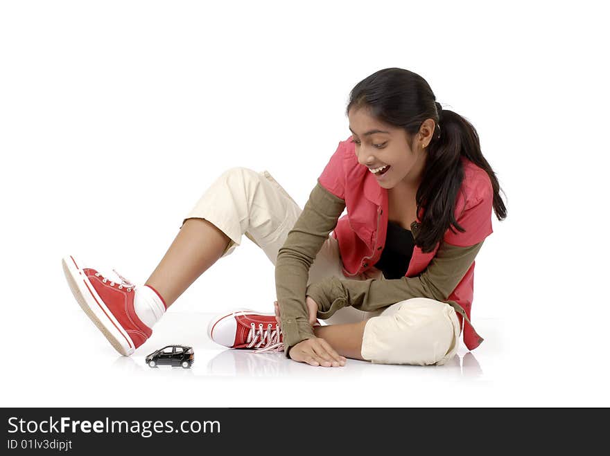 Beautiful girl looking at her dream car model over white background. Beautiful girl looking at her dream car model over white background