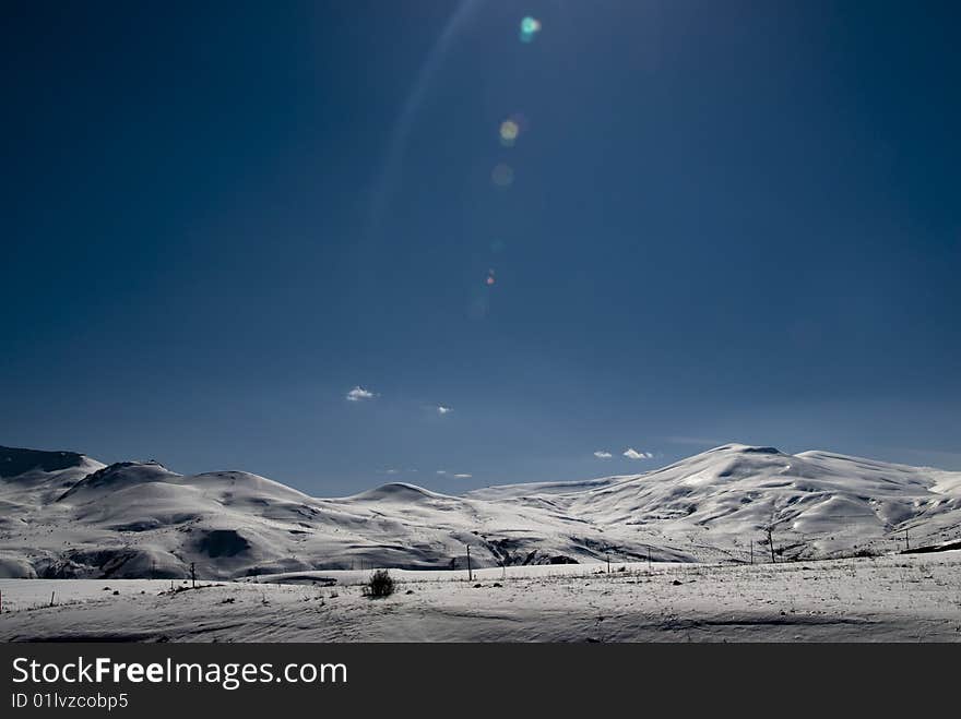 Snowcapped mountain range with lens flare. Snowcapped mountain range with lens flare.