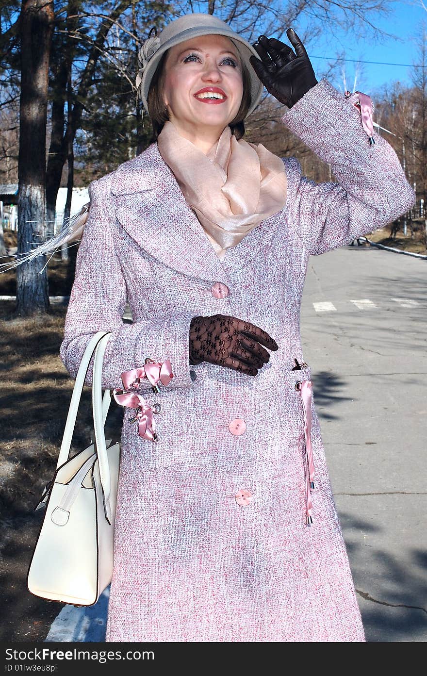 Stylish young woman - lady in coat and lady's hat with handbag (purse) on the street. Stylish young woman - lady in coat and lady's hat with handbag (purse) on the street.