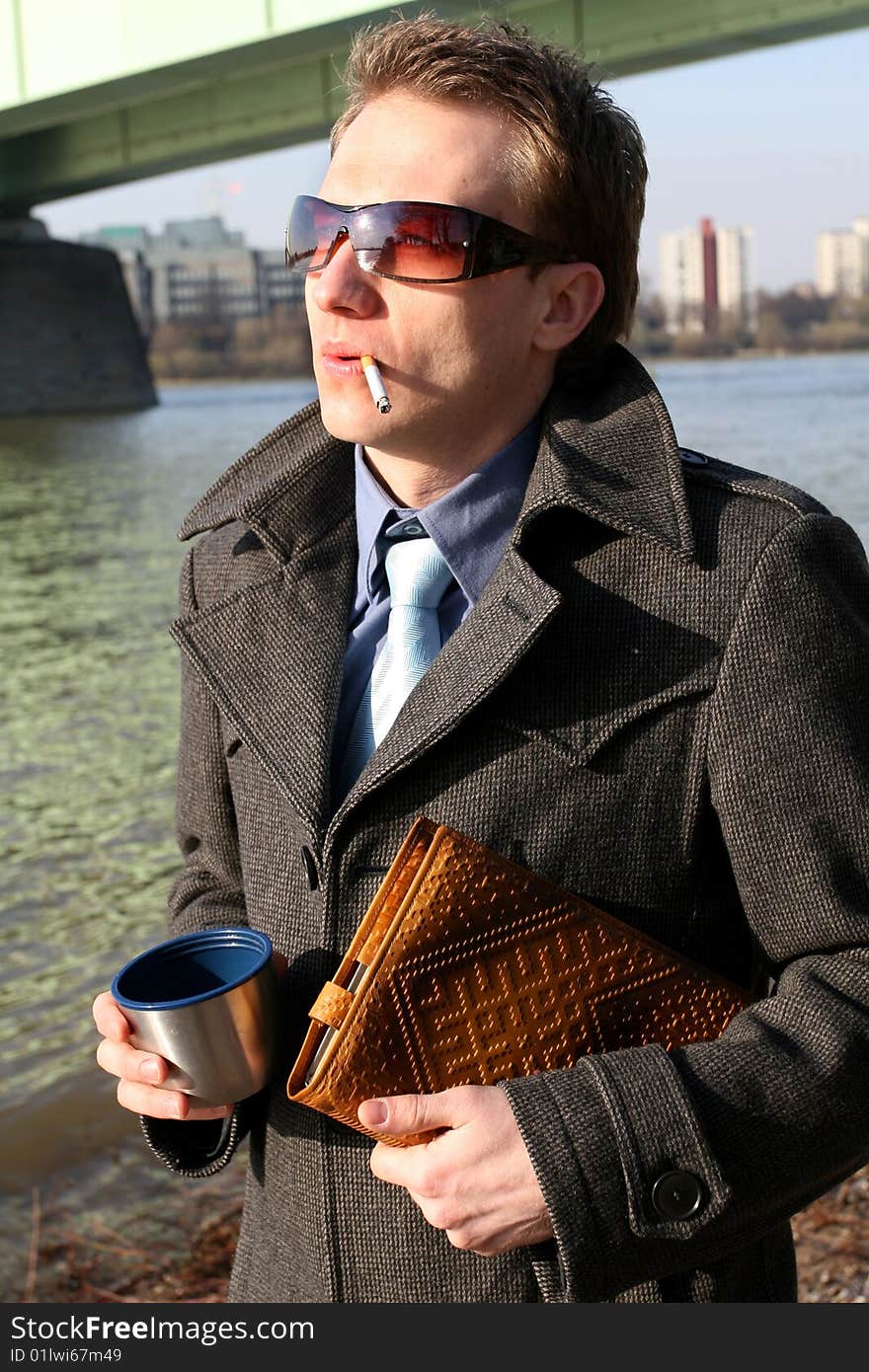 Man smoking and holding a cup tea and book in his hands. Man smoking and holding a cup tea and book in his hands