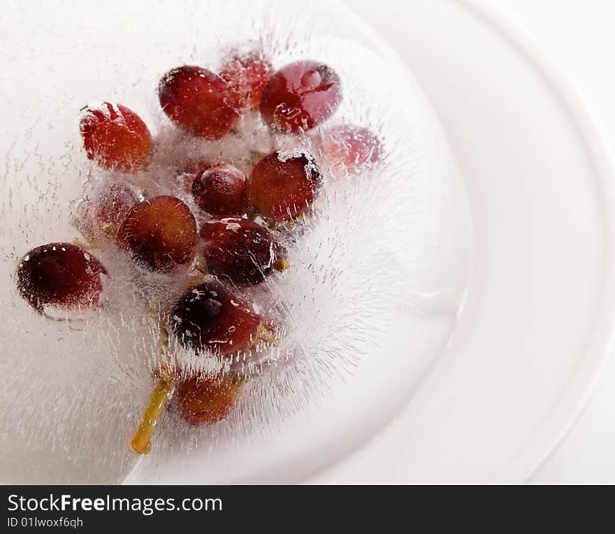 Grape fruit frozen in a ice block on a white plate. Grape fruit frozen in a ice block on a white plate