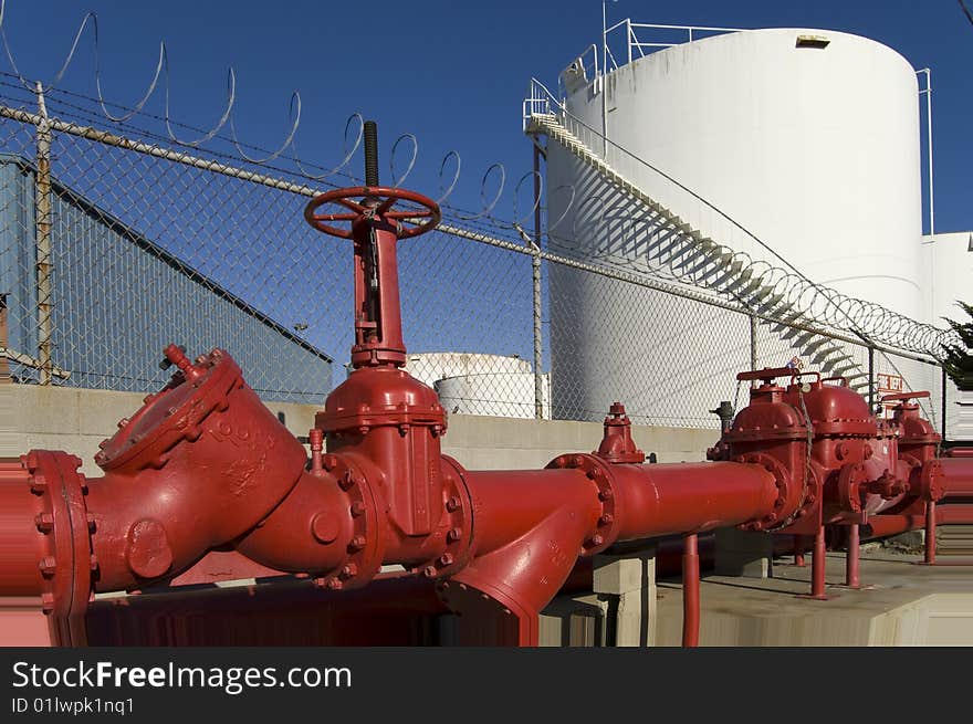 A chemical storage tank and large iron pipes are part of a liquid chemical storage facility. A chemical storage tank and large iron pipes are part of a liquid chemical storage facility.