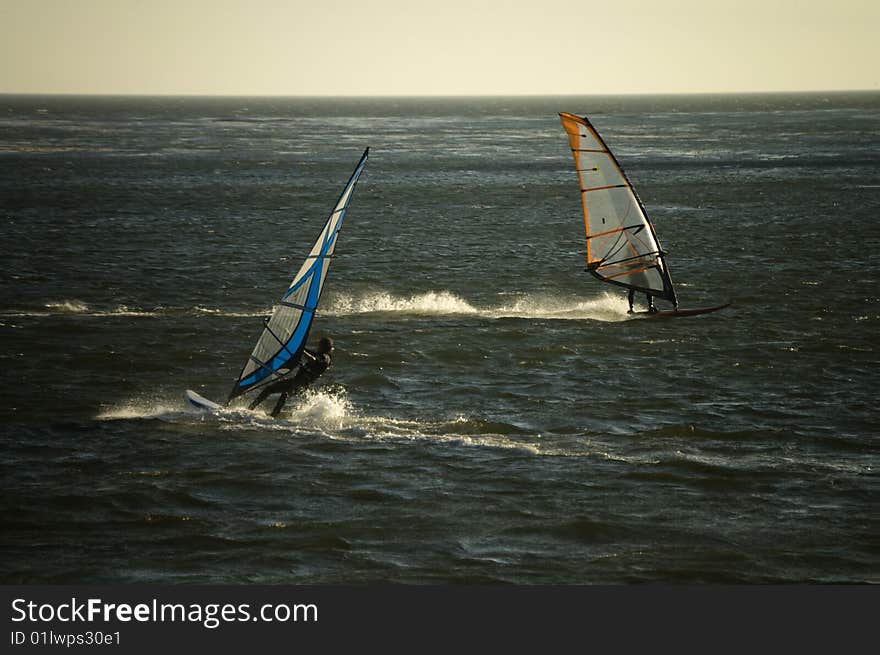 Two wind surfers cross paths in the ocean. Two wind surfers cross paths in the ocean.