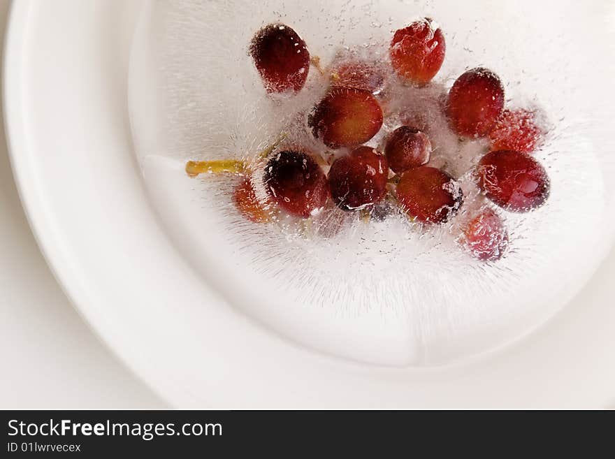 Grape fruit frozen in a ice block on a white plate. Grape fruit frozen in a ice block on a white plate