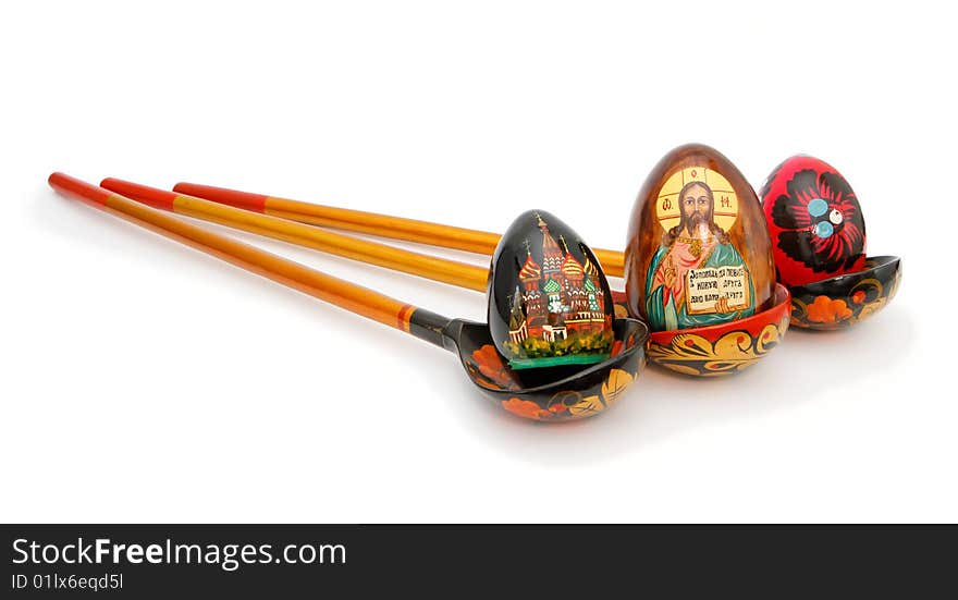 Three Easter eggs in Russian wooden hand-painted spoons with long handles on white background. Three Easter eggs in Russian wooden hand-painted spoons with long handles on white background