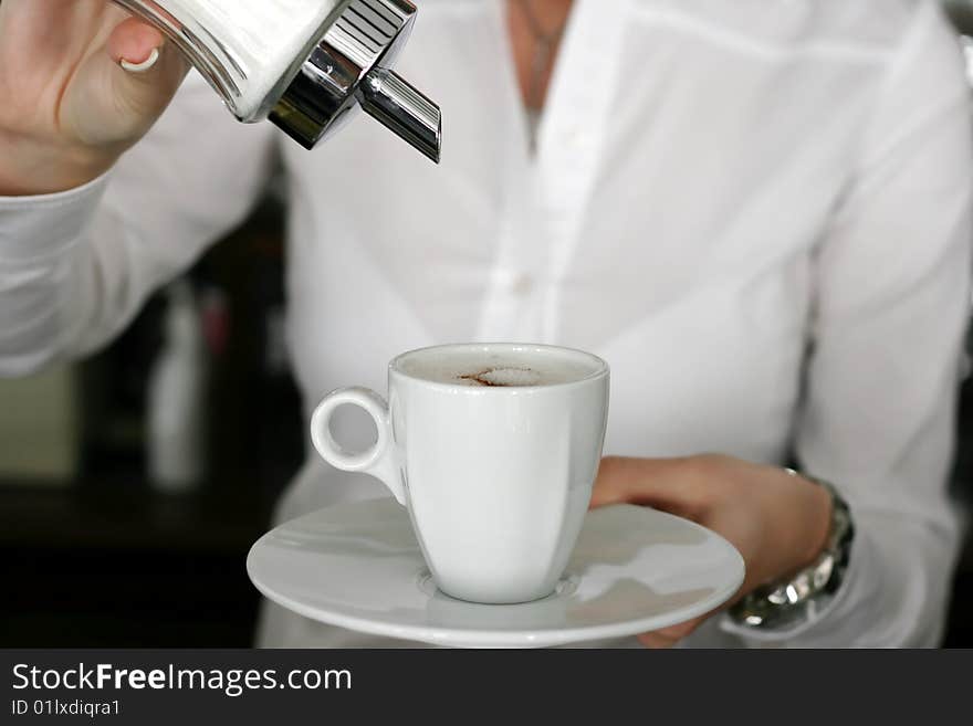 Young waitress adjusting a cup of coffee. Young waitress adjusting a cup of coffee