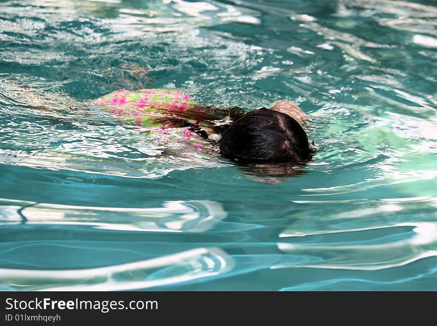 Little girl swimming  across the pool