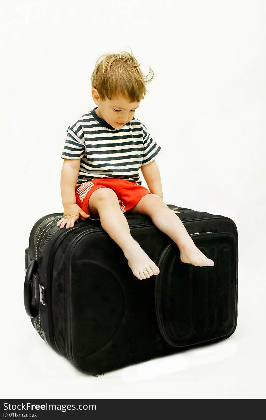 Young boy on big black suitcase