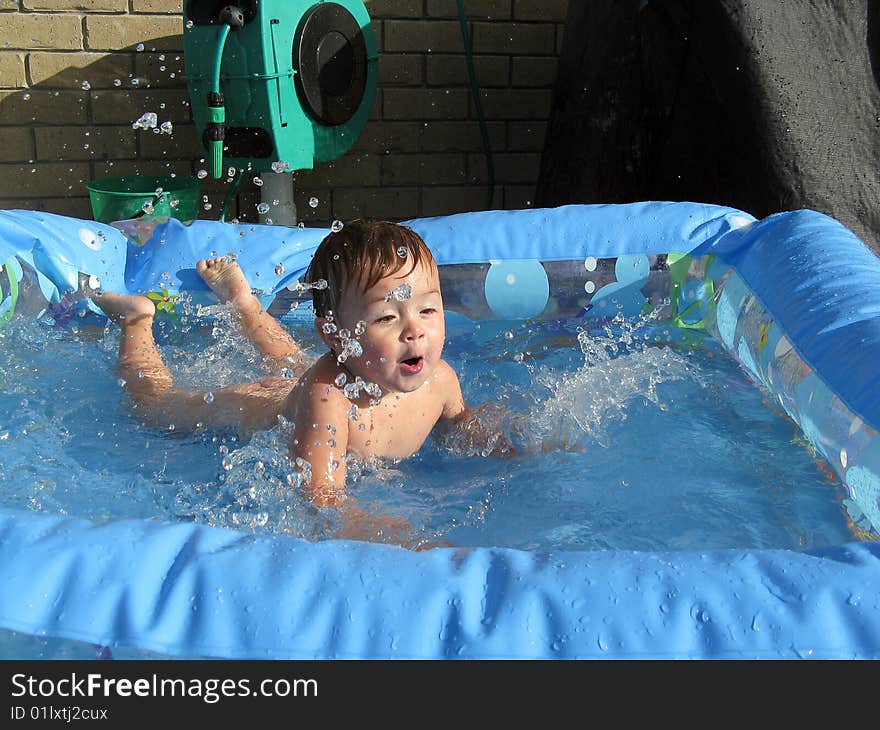 A male toddler diving into a paddling pool with water splashing up. A male toddler diving into a paddling pool with water splashing up.