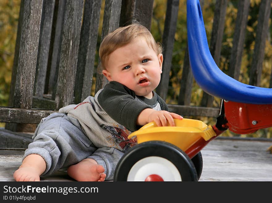 Cute little boy playing with his tricycle