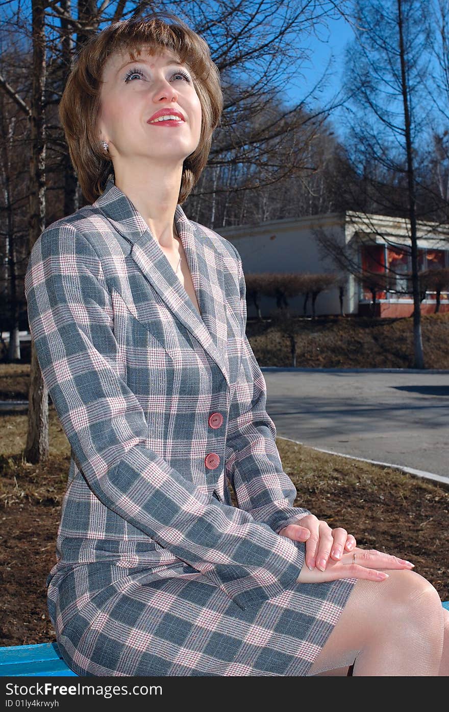 Stylish young woman - lady in checkered (chequered) suit sit on the bench. Stylish young woman - lady in checkered (chequered) suit sit on the bench.