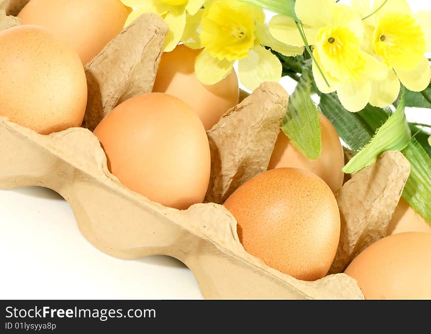 Eggs in box with flowers isolated on white