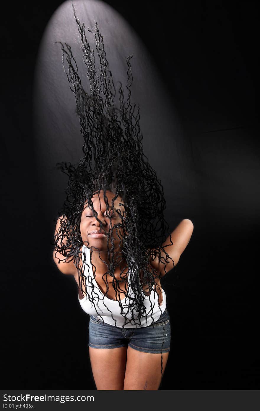 Wind - lovely young afro-american woman with long flapping hairs against black background