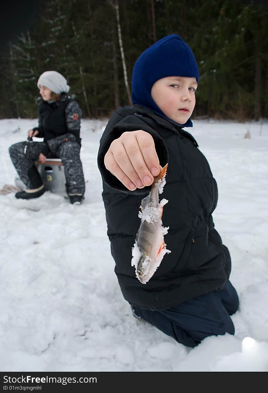 A young boy holding up the fish he has just caught. A young boy holding up the fish he has just caught.