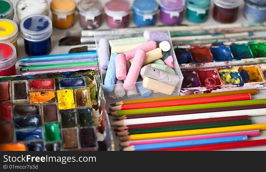 Items for drawing and art: crayons, watercolor paints, brushes, colored pencils.