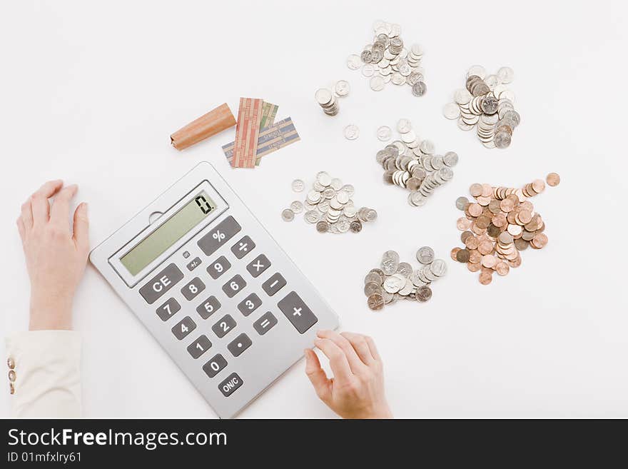 Hands using calculator with various piles of coins. Hands using calculator with various piles of coins