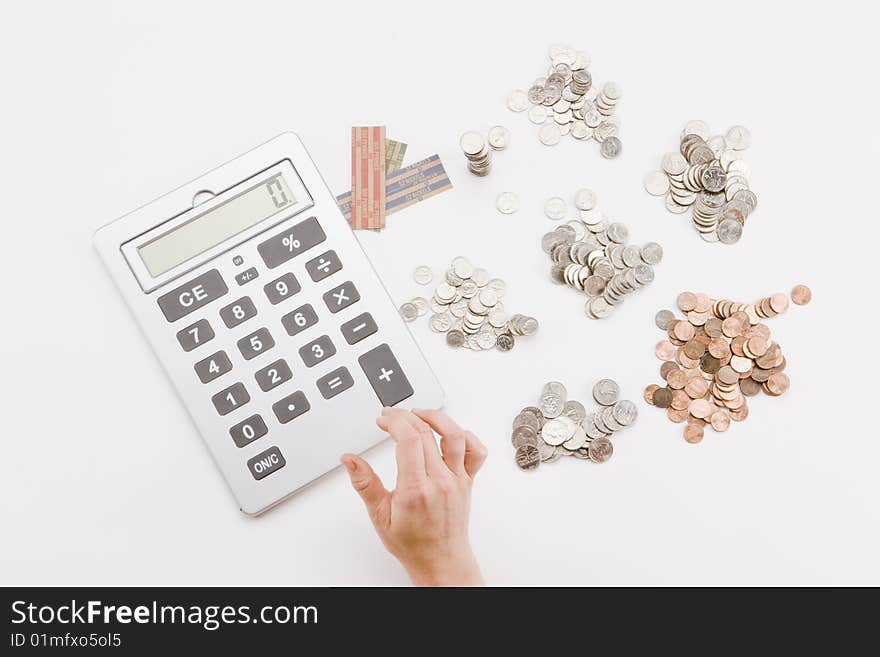 Single hand using calculator to add piles of coins. Single hand using calculator to add piles of coins